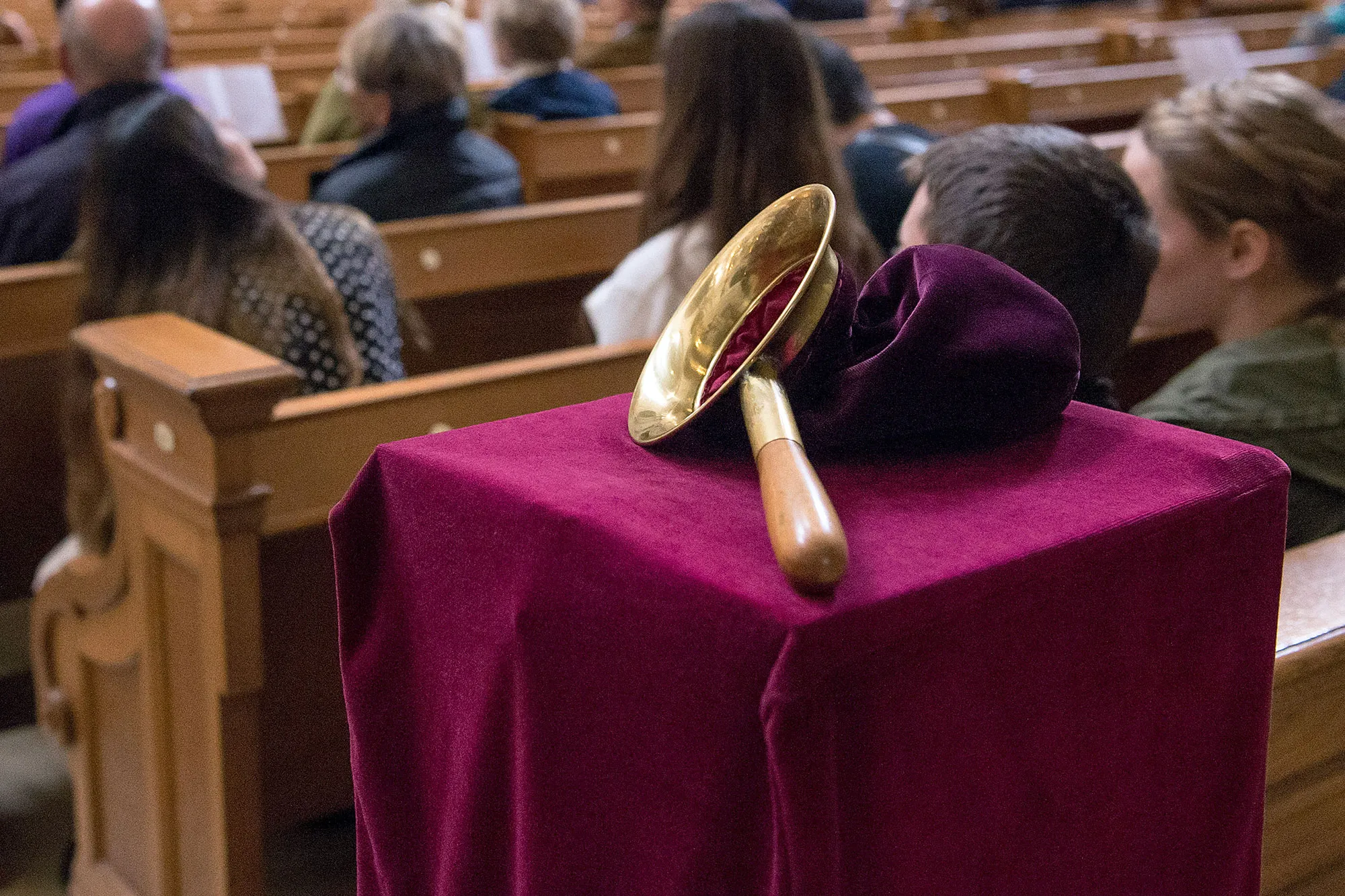 In einer Kirche liegt ein Opferbeutel auf einer Decke aus Samt