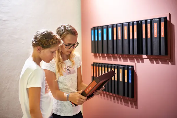 Zwei Mädchen lesen im Bücher-Buch über das biblische Buch Philipper