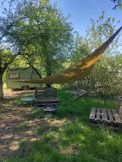 Wiese mit Hängematte und Wohnwagen