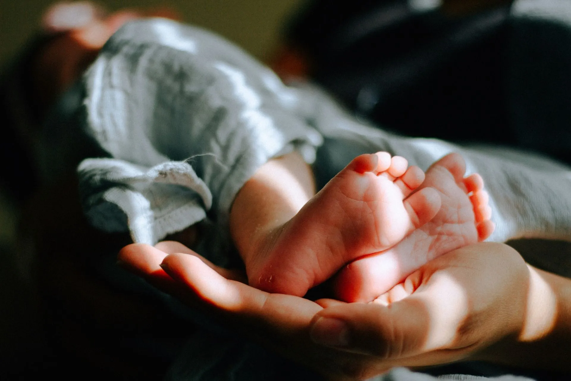 Hand, die Babyfüsse hält