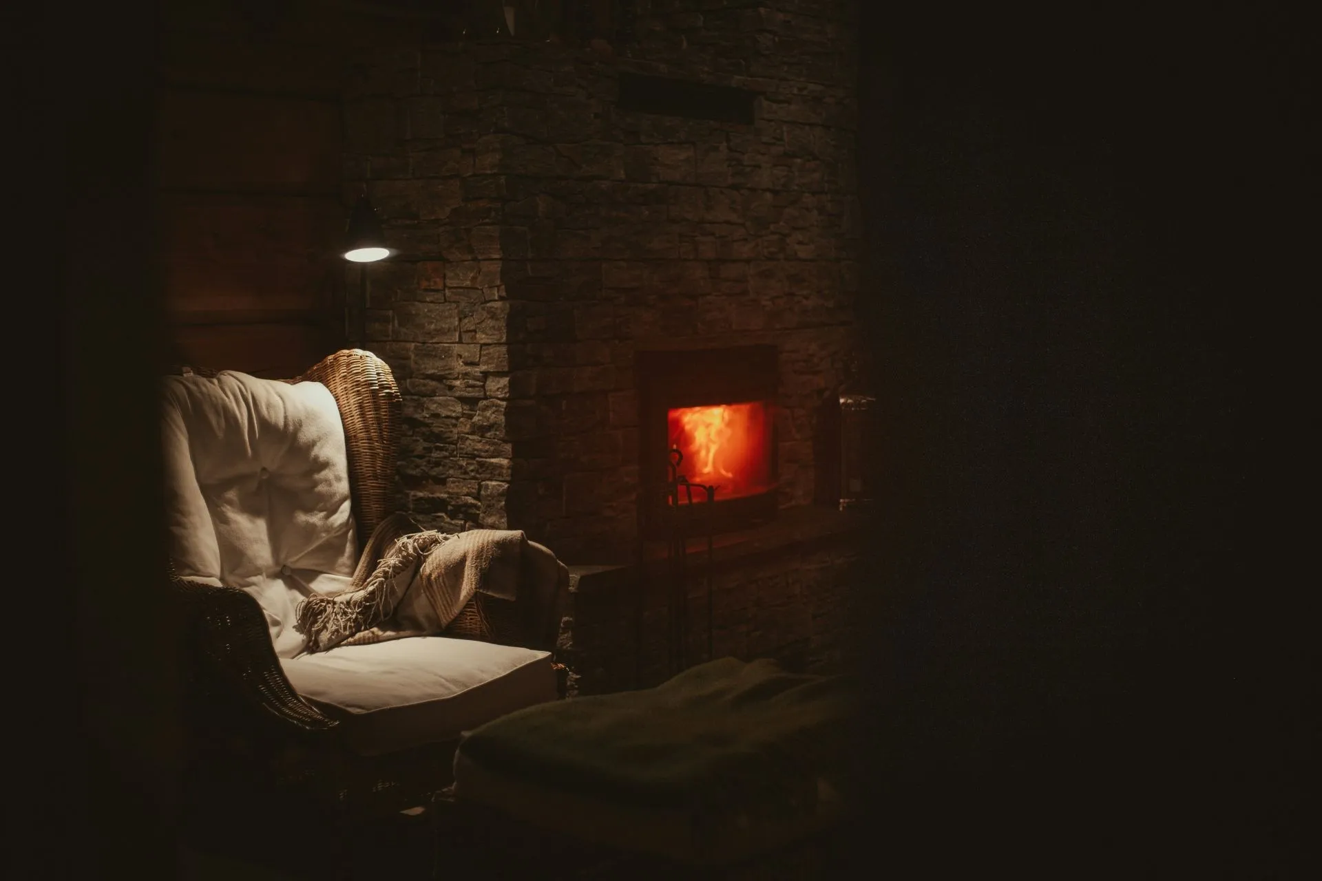 Gemütlicher Sessel mit Decke neben brennendem Kamin