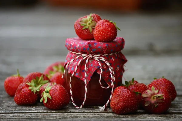 Glas mit Erdbeermarmelade und weiteren Erdbeeren