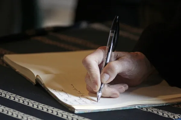 Hand mit Stift und Notizbuch