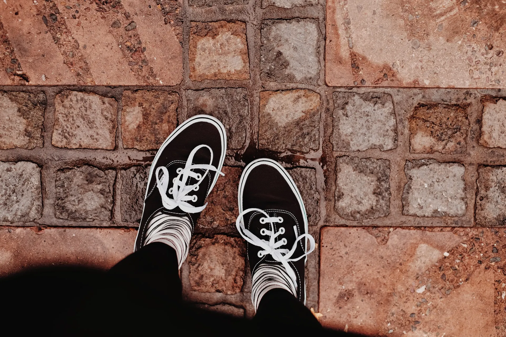 Quelle: Valeriia Miller on Unsplash Blick von oben auf zwei Füße, die auf Pflastersteinen stehen