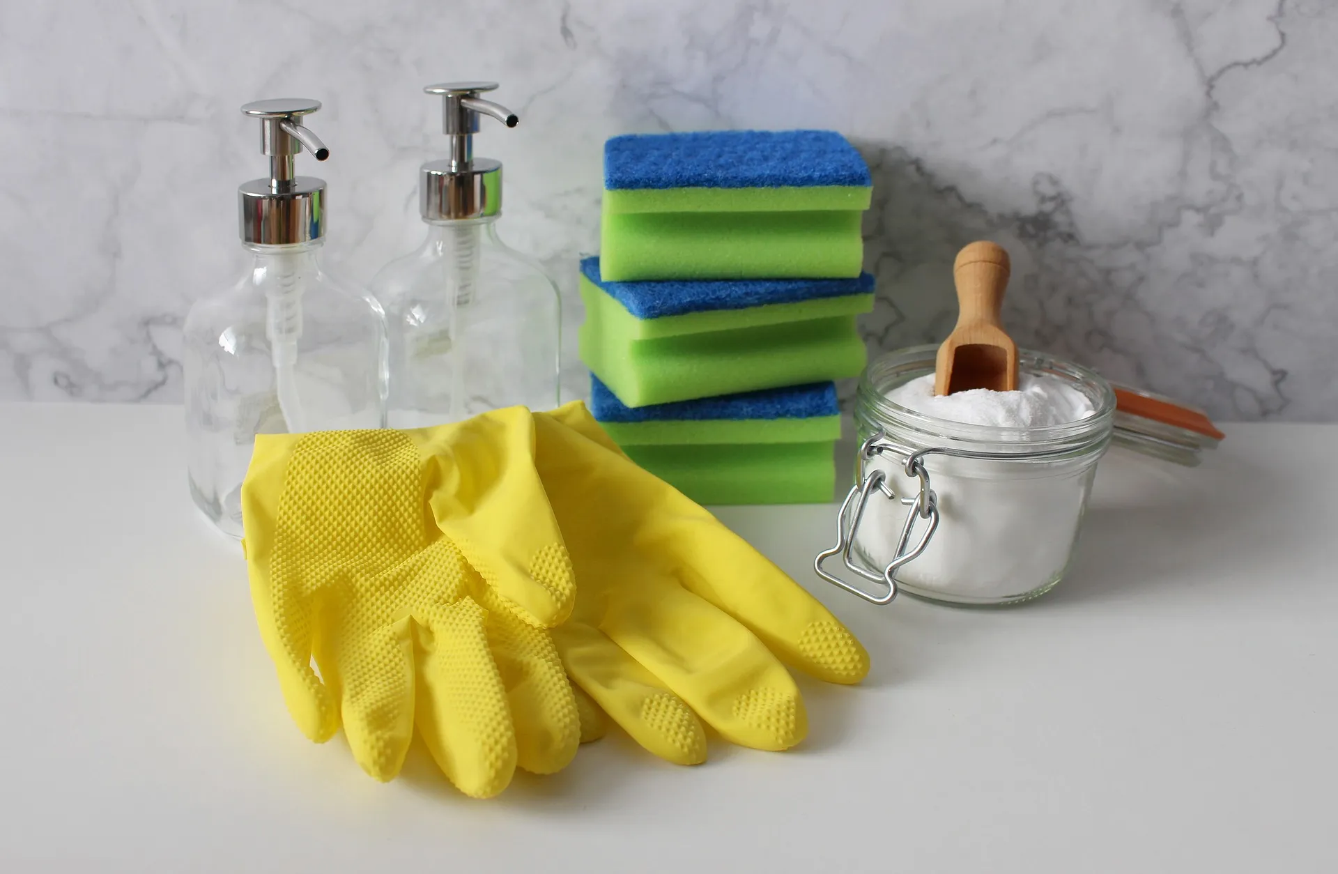 Schwamm, Putzhandschuhe und Putzmittel im Glas