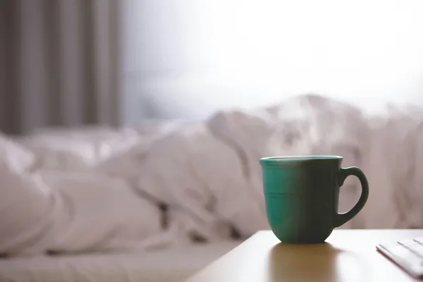 Kaffeetasse vor leerem Bett