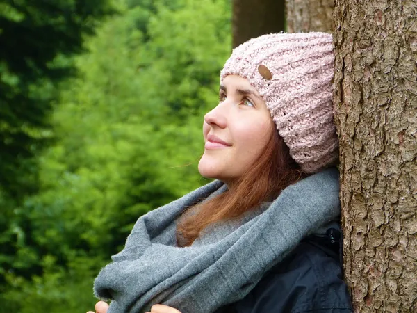 junge Frau an Baum gelehnt