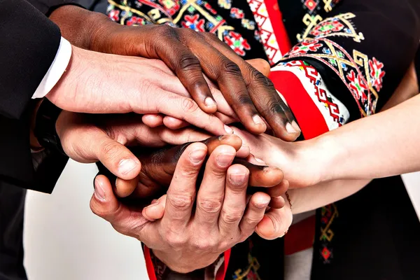 Vier Menschen legen ihre Hände übereinander