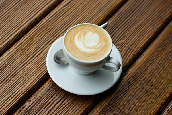 Tasse mit Milchkaffee auf Holztisch