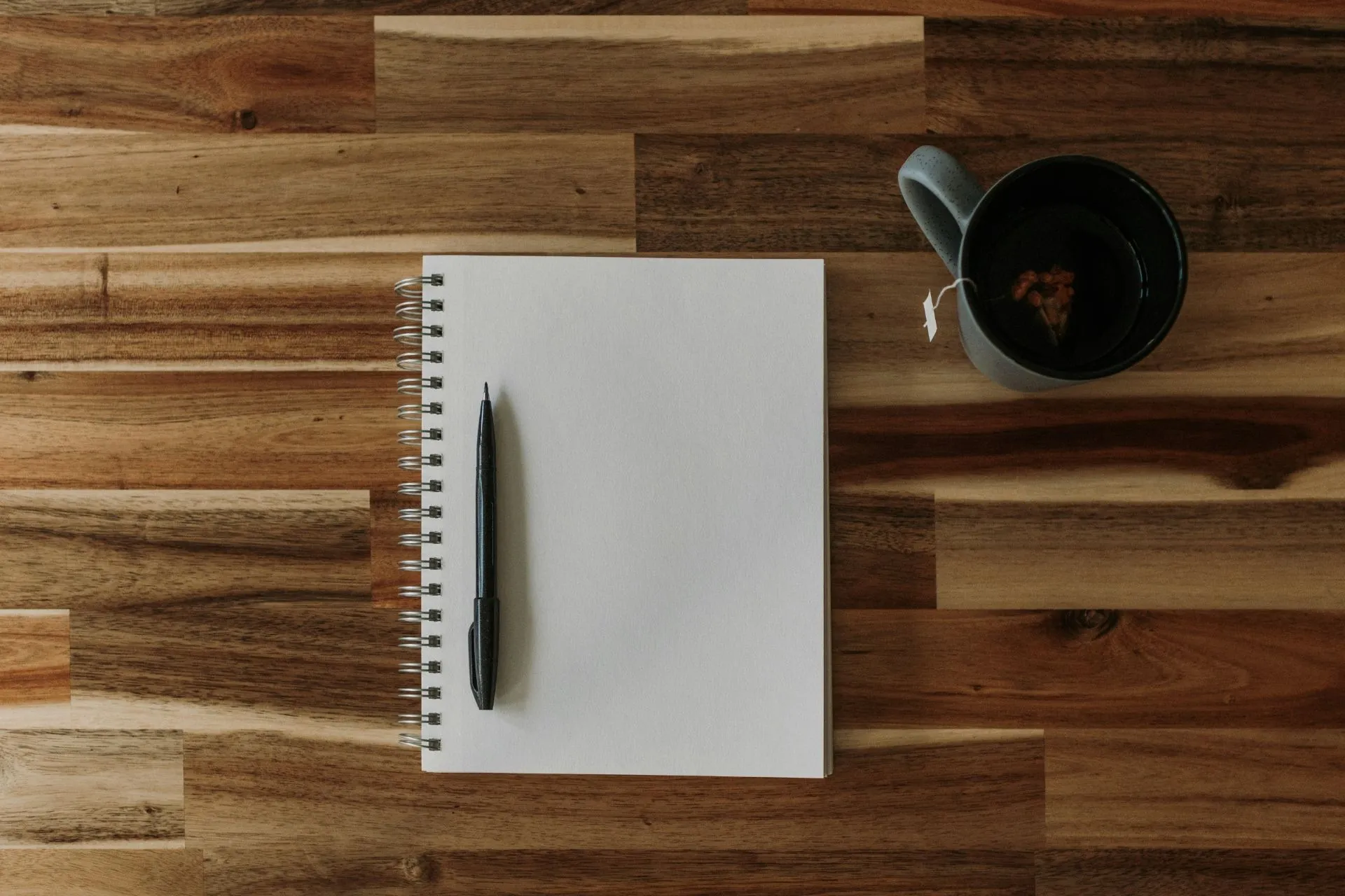 Notizblock, Stift und Tasse auf Holztisch