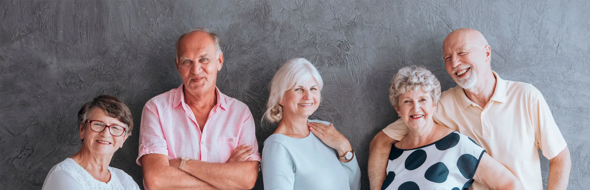 Quelle: Photographee / stock.adobe.com Fünf Senioren und Seniorinnen stehen nebeneiander vor einer Wand.