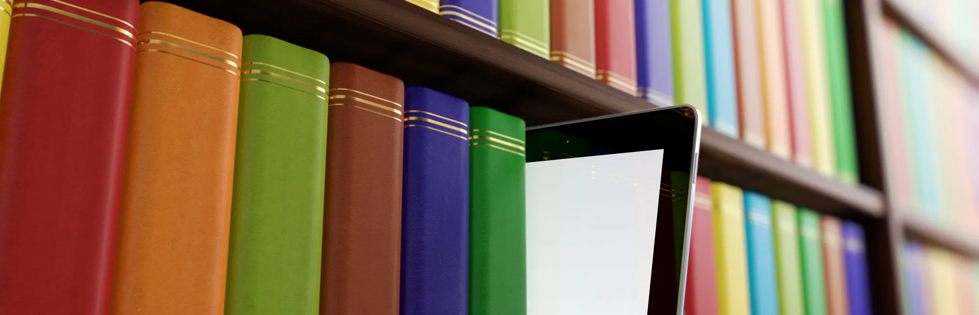 Quelle: vasabii - stock.adobe.com Regal einer Bibliothek mit Büchern und einem Tablet