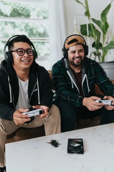 Quelle: Samsung Memory, Unsplash zwei junge Männer sitzen zusammen auf der Couch und spielen mit Controllern ein Videospiel. Sie haben Spaß.